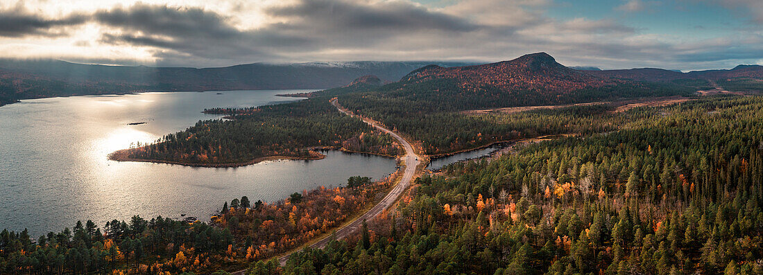 Straße durch Landschaft mit See und Bergen im Stora Sjöfallet Nationalpark im Herbst in Lappland in Schweden von oben\n