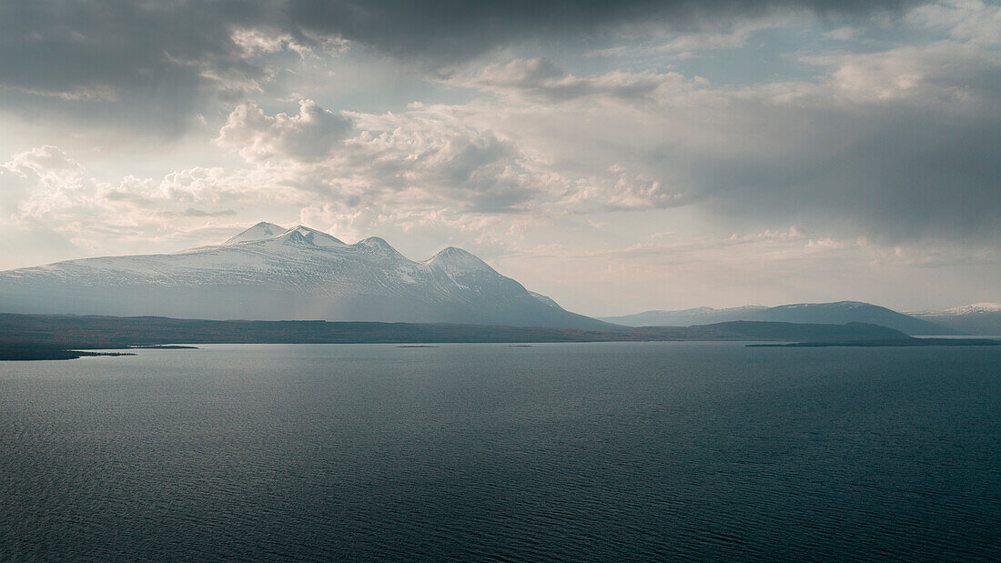 Landschaft mit verschneiten Bergen des Sarek Nationalparks und See im Stora Sjöfallet Nationalpark im Sonnenuntergang in Lappland in Schweden\n