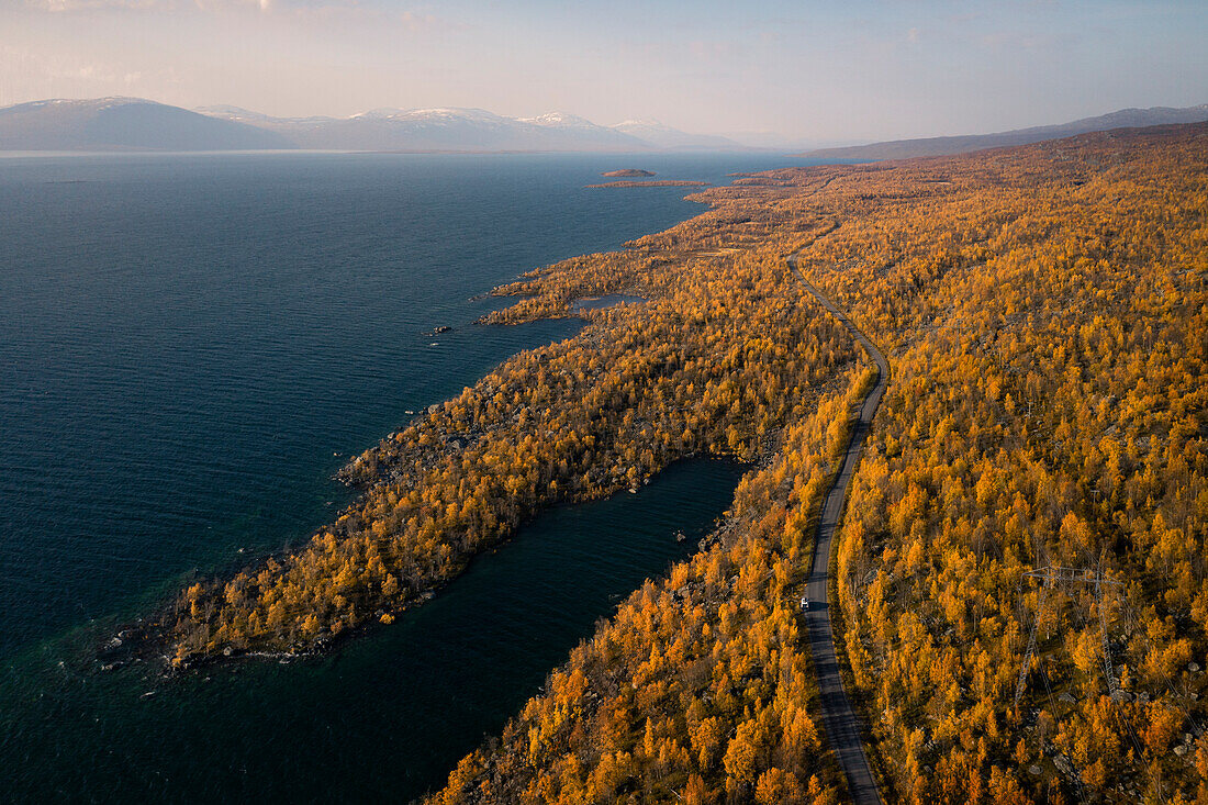 Camping mit Campervan in Landschaft mit Bergen und See im Stora Sjöfallet Nationalpark im Herbst in Lappland in Schweden von oben\n