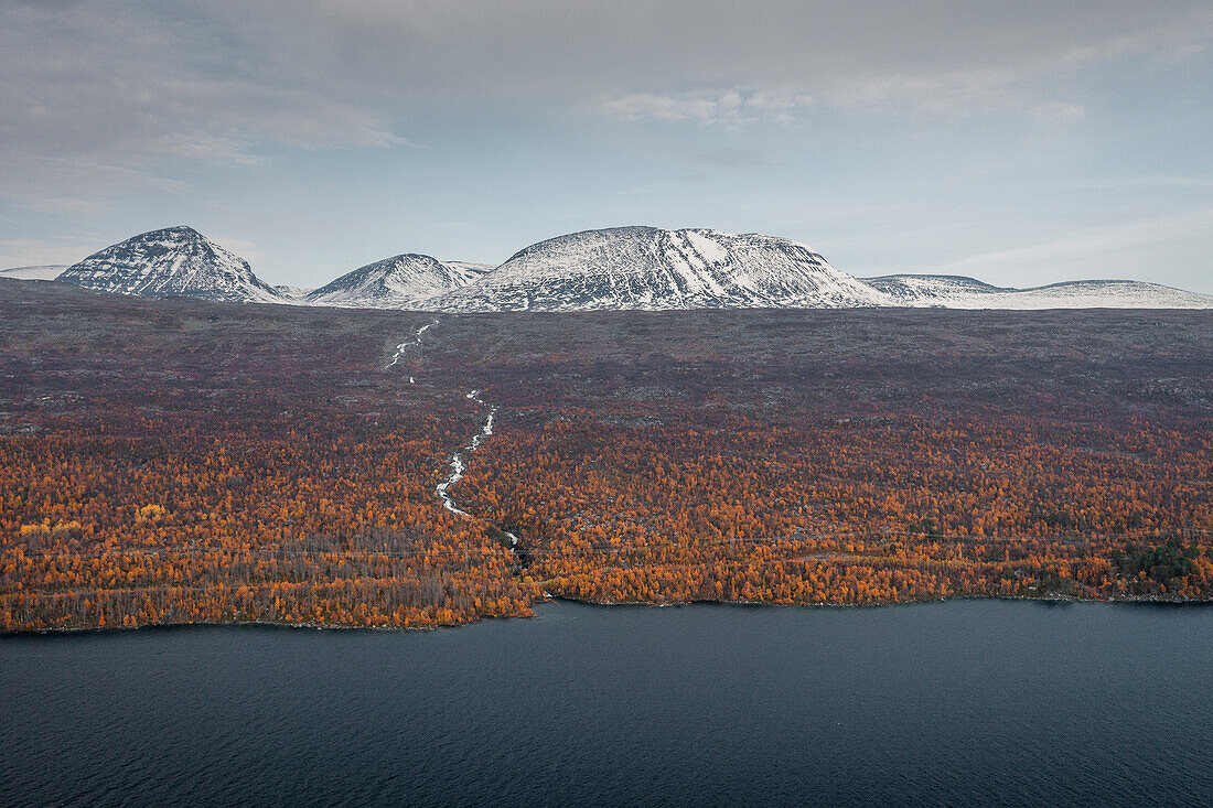 Landscape with snowy mountains and river to the lake in Stora Sjöfallet National Park in autumn in Lapland in Sweden
