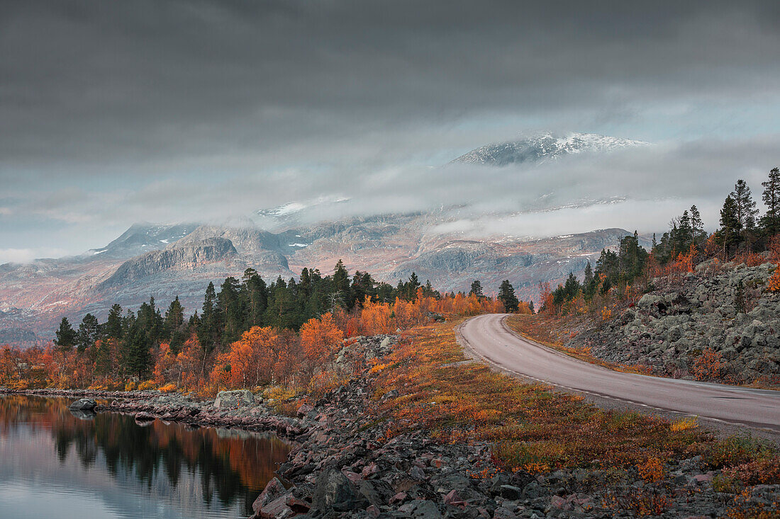 Straße in die Landschaft mit Bergen und See im Stora Sjöfallet Nationalpark im Herbst in Lappland in Schweden\n