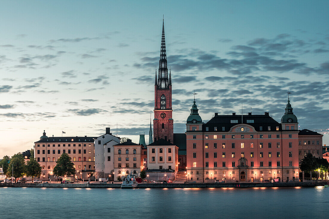 Beleuchtete Skyline von Stockholm bei Nacht mit Kirche Riddarholmskyrkan auf Altstadtinsel Gamla Stan in Schweden\n