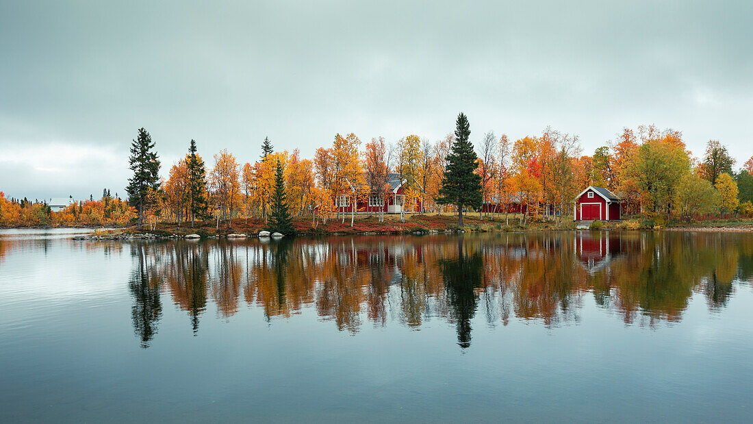 Rotes Haus am See im Herbst entlang der Wilderness Road in Lappland in Schweden\n