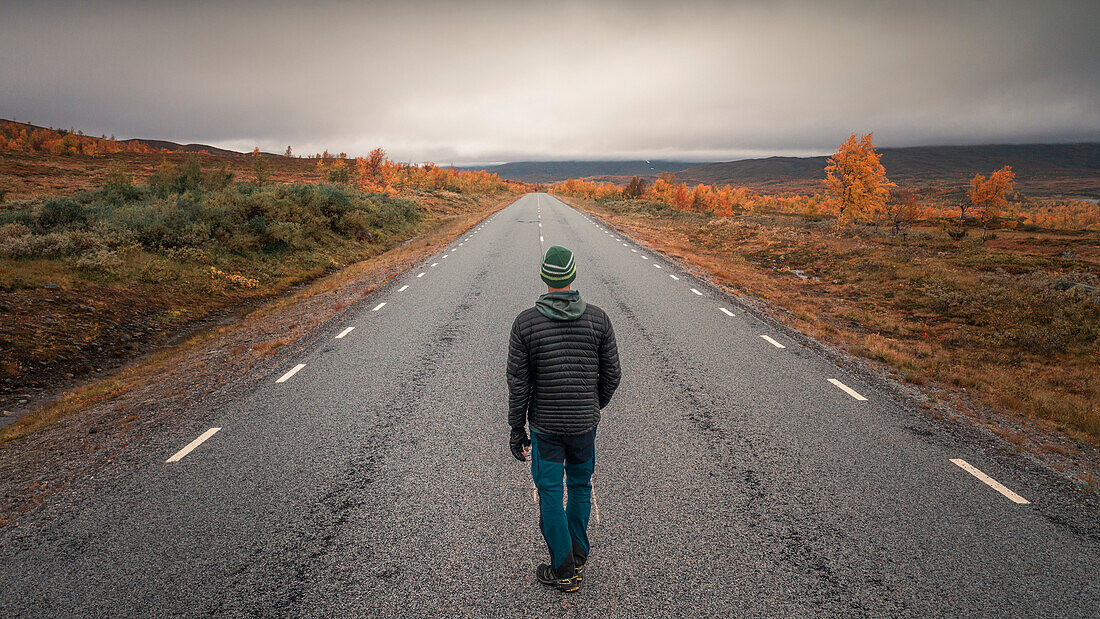 Person auf der Straße der der Wilderness Road, auf der Hochebene Vildmarksvägen in Jämtland im Herbst in Schweden\n