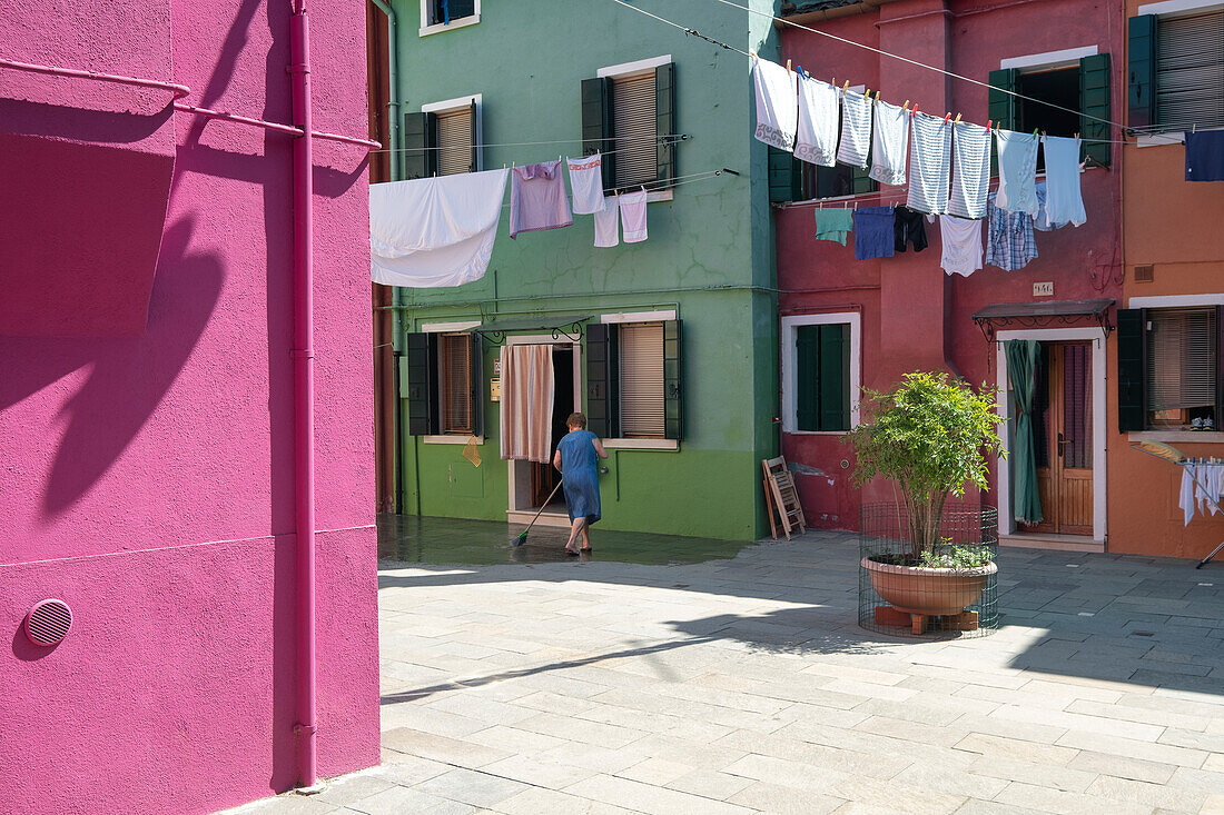 View of alley with clothesline between colorful house facades, Burano fishing island, Venice, Veneto, Italy, Europe