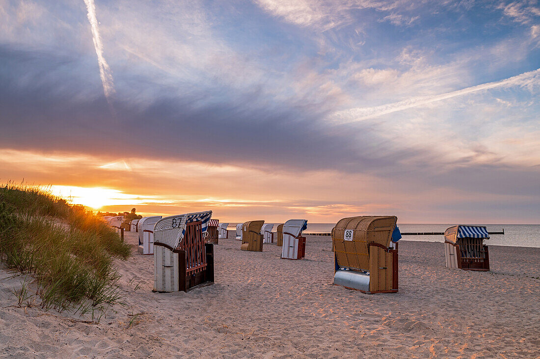 Strandkörbe vor der aufgehenden Sonne in Großenbrode, Ostsee, Ostholstein, Schleswig-Holstein, Deutschland
