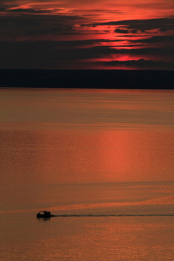 Red sunset over boat on water, Kvarner, Croatia