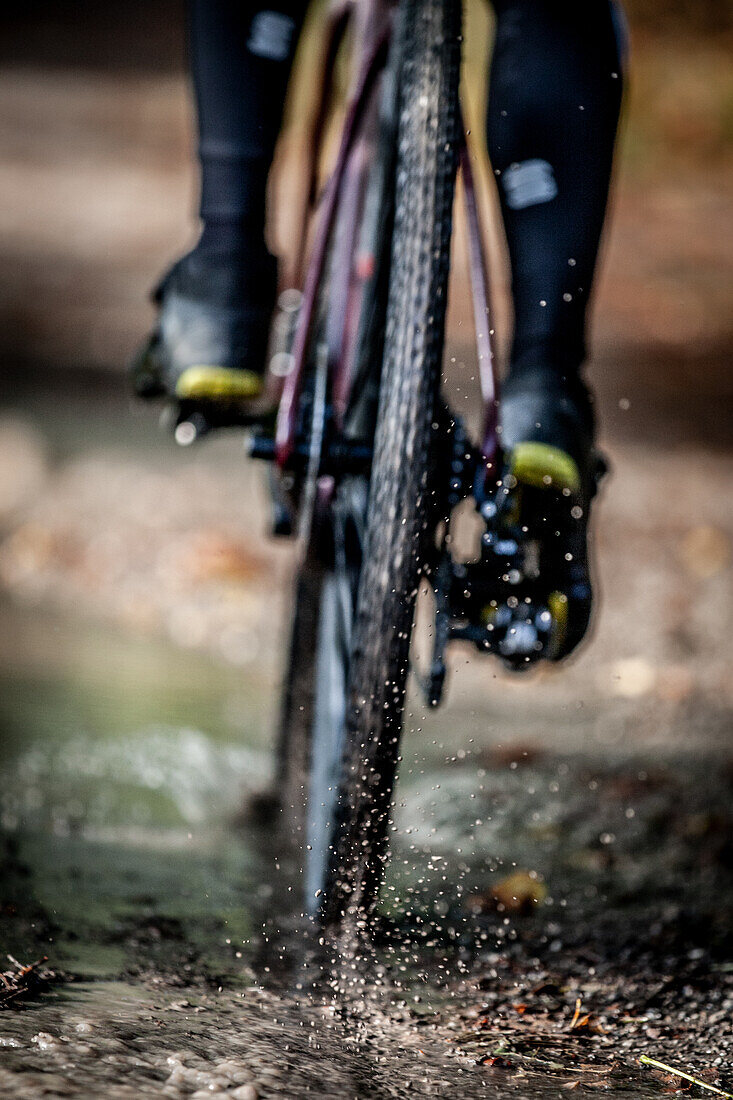 Autumn weather. Gravel biker drives through puddle