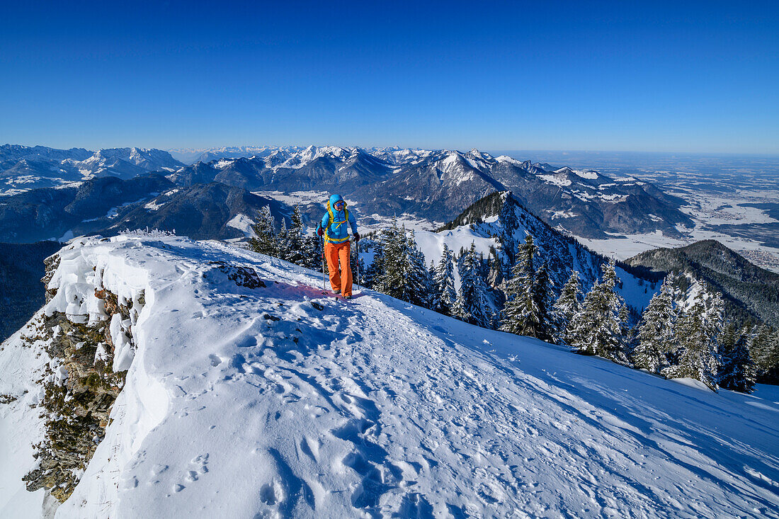 Frau beim Wandern steigt über verschneiten Hang zum Hochgern auf, Chiemgauer Alpen im Hintergrund, Hochgern, Chiemgauer Alpen, Oberbayern, Bayern, Deutschland