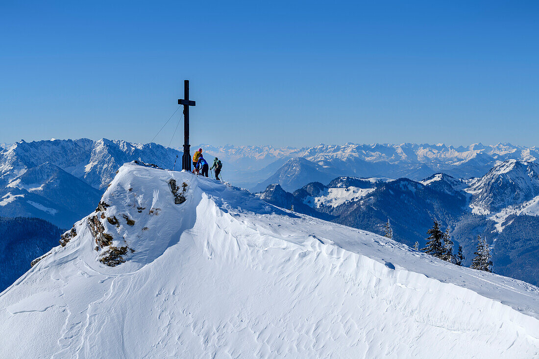 Several people stand at the summit cross of the Hochgern, Kaiser Mountains and Central Alps in the background, Hochgern, Chiemgau Alps, Upper Bavaria, Bavaria, Germany