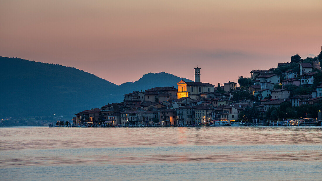 Dorf Peschiera Maraglio auf der Insel Monte Isola am Iseosee mit Dorfkirche bei Sonnenuntergang, Italien