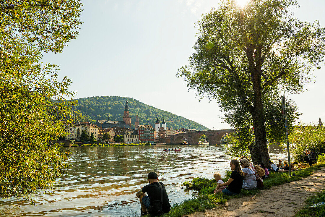 Young people in the evening sun at the Neckar, Heidelberg, Baden-Württemberg, Germany