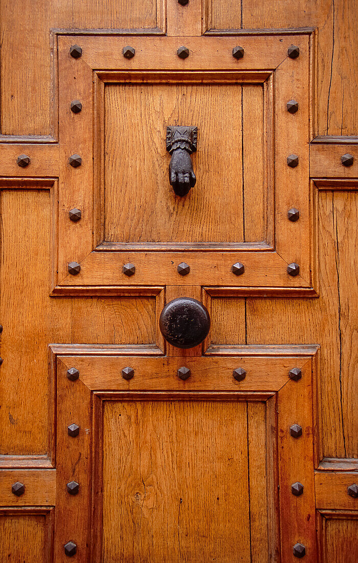 Large panneled and studded door with iron knob and knocker
