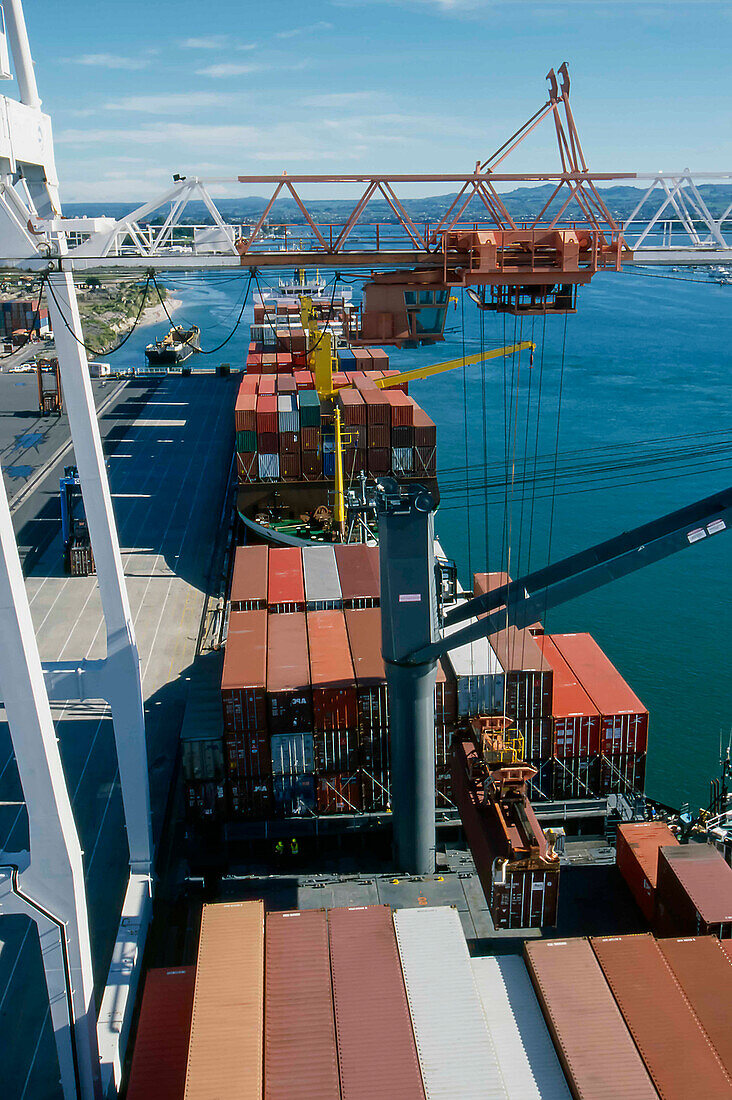 Blick von der Spitze des Krans auf Schiffscontainer, die auf das Deck eines Schiffes geladen werden