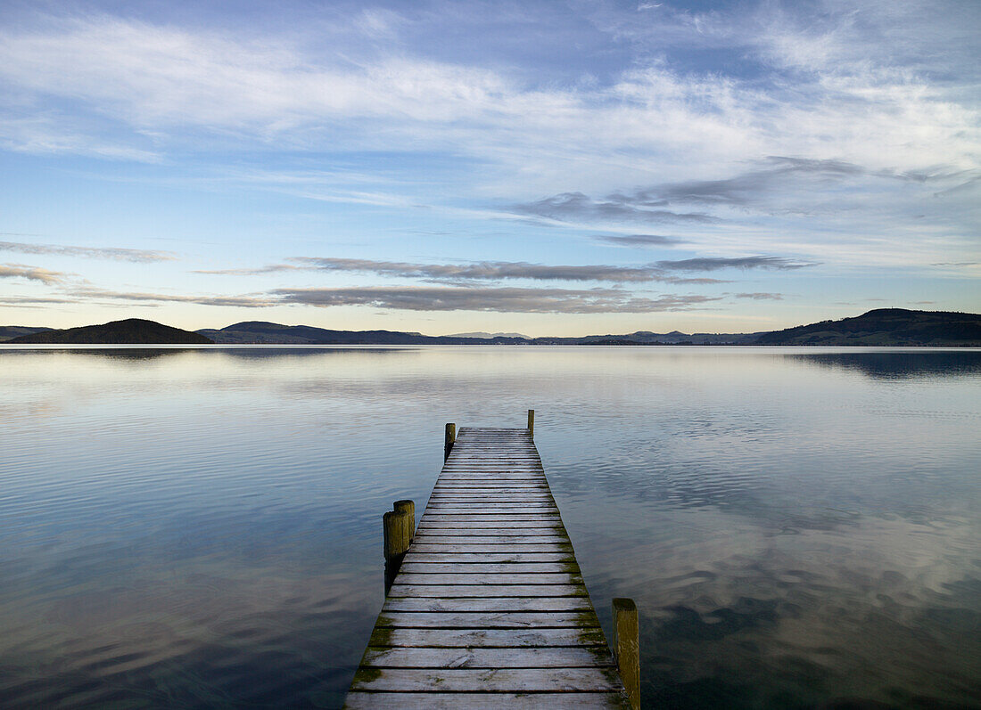Wooden jetty spanning out over lake early evening