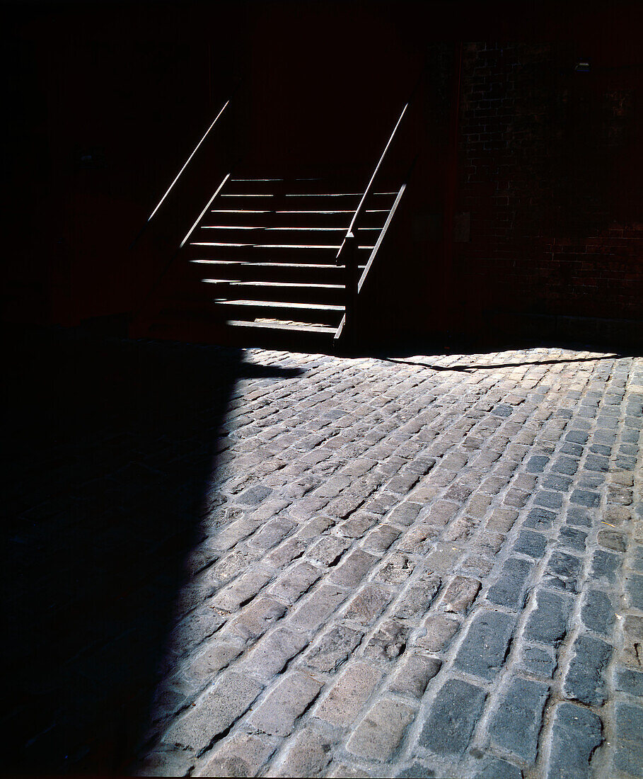 Old wooden stairs and old brick courtyard in part shadow