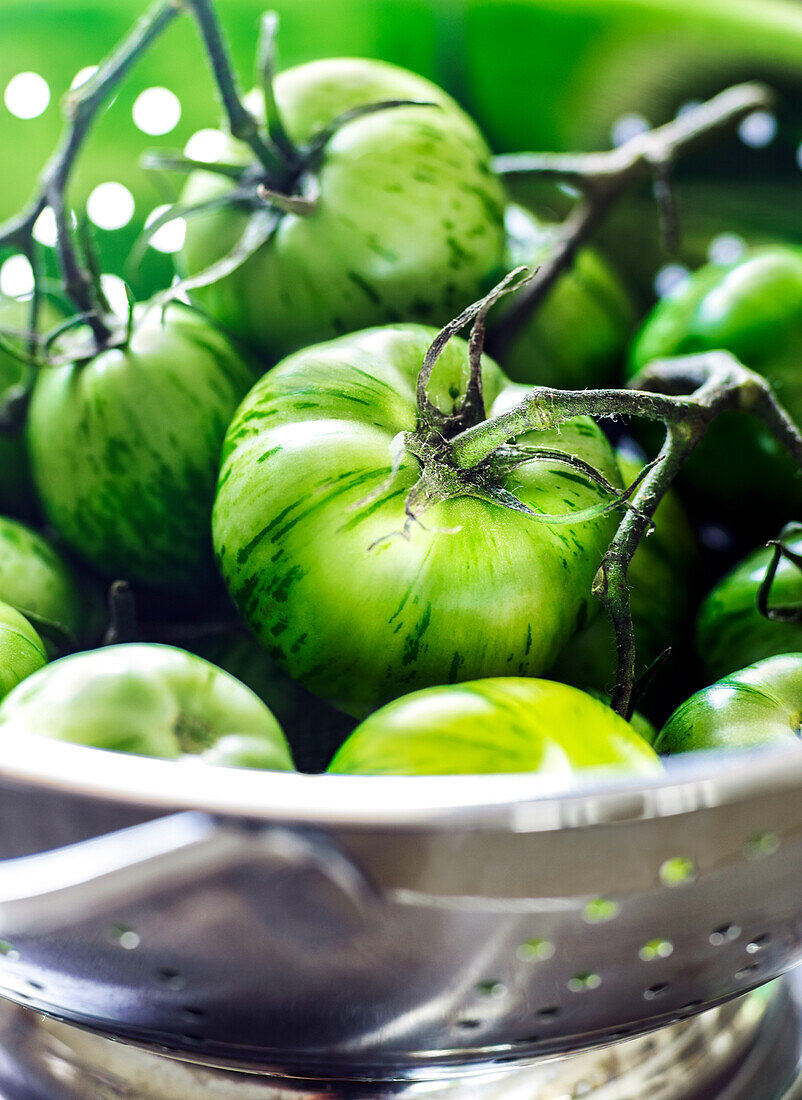 Metallsieb voller grüner Tomaten