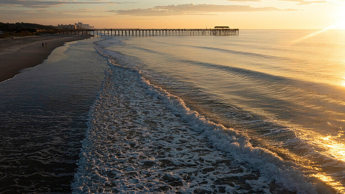 Dawn on South Carolina beach with walkers.