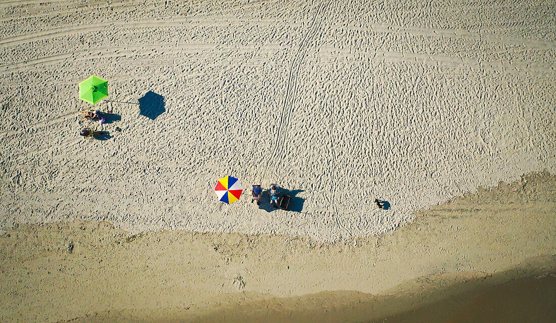 Obenliegende Aufnahme von zwei Sonnenschirmen an einem Strand