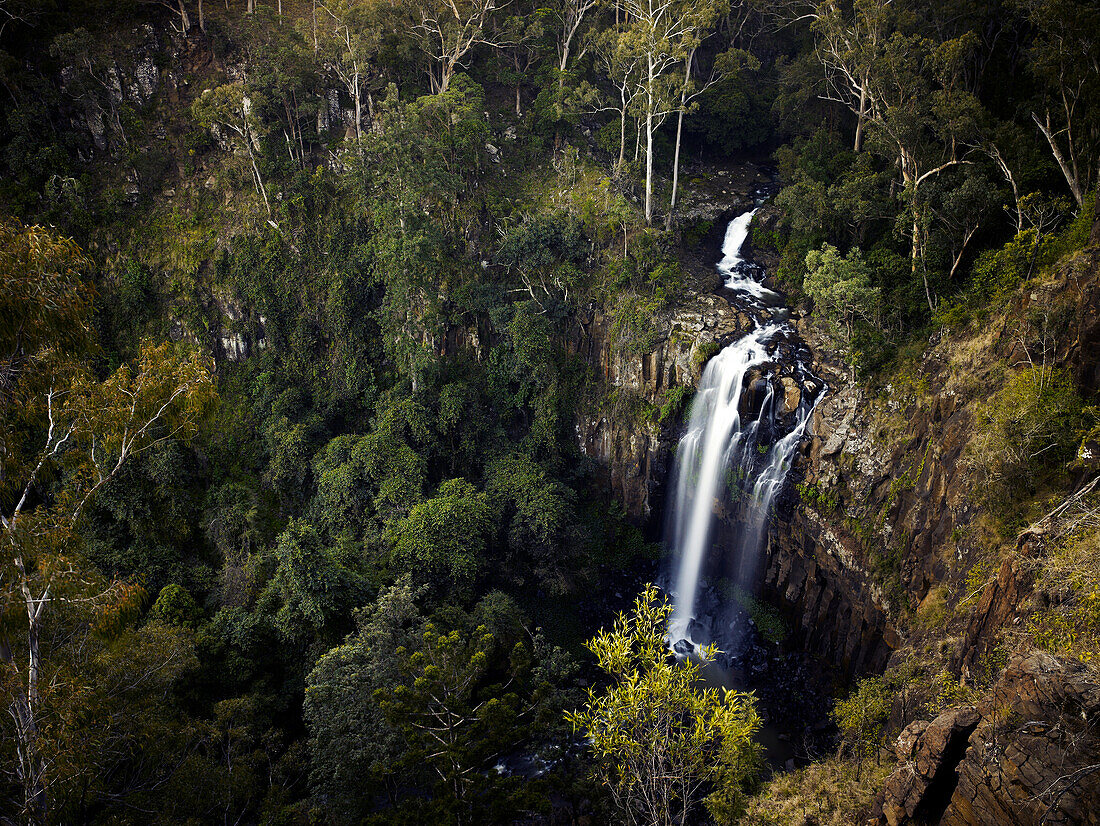 Luftaufnahme des Stroms, der durch den australischen Ureinwohnerbusch fließt und die felsige Klippenwand in den darunter liegenden natürlichen Pool hinunterfließt