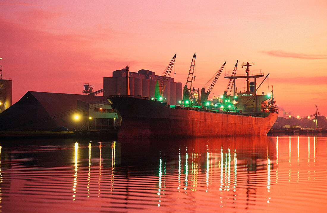 Containerschiff angedockt an einem kommerziellen Dock in der Abenddämmerung, Mississippi River, Mississippi, USA