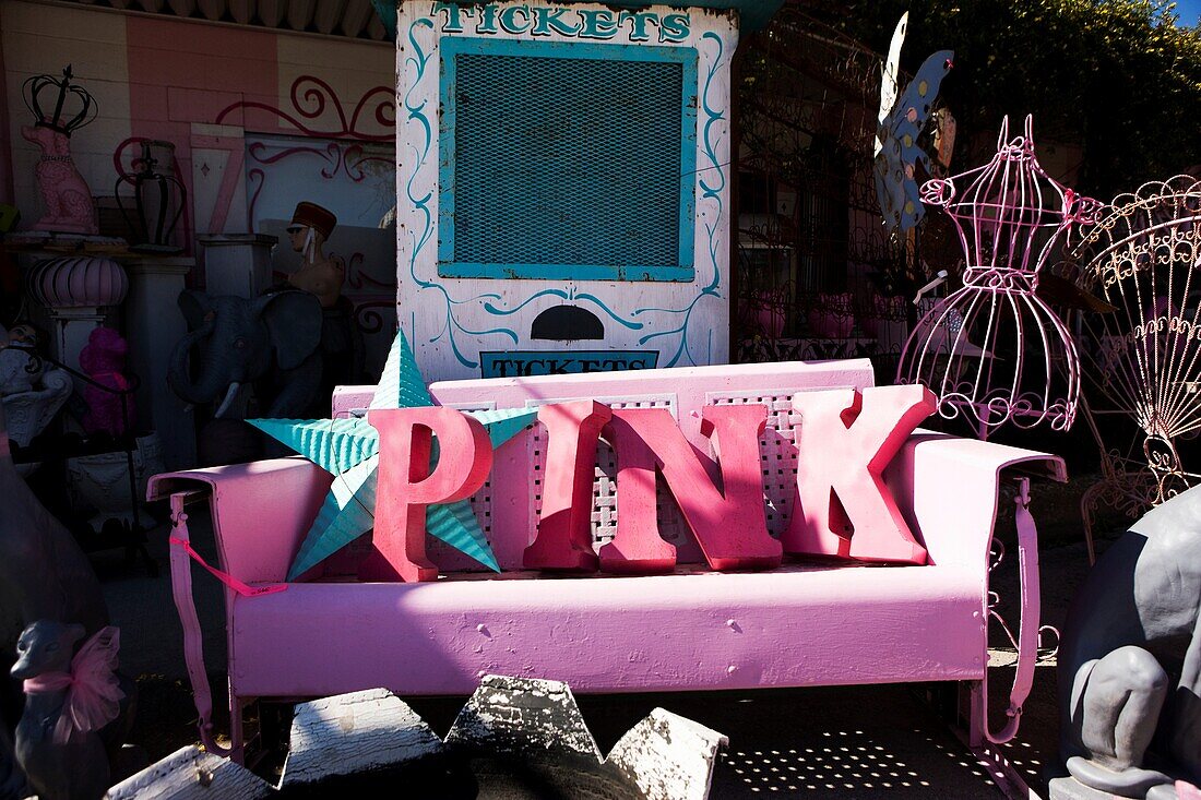 Buchstaben, die das Wort PINK auf einer Vintage-Eisenbank in einem Kuriositätenladen buchstabieren