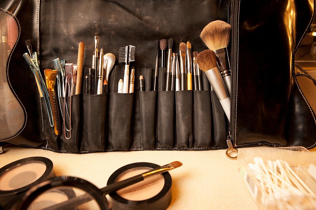 Make-up-Pinsel, Clips, Kämme und Wattestäbchen in einer Make-up-Stylisten-Tasche auf einem Tresen in einer Umkleidekabine