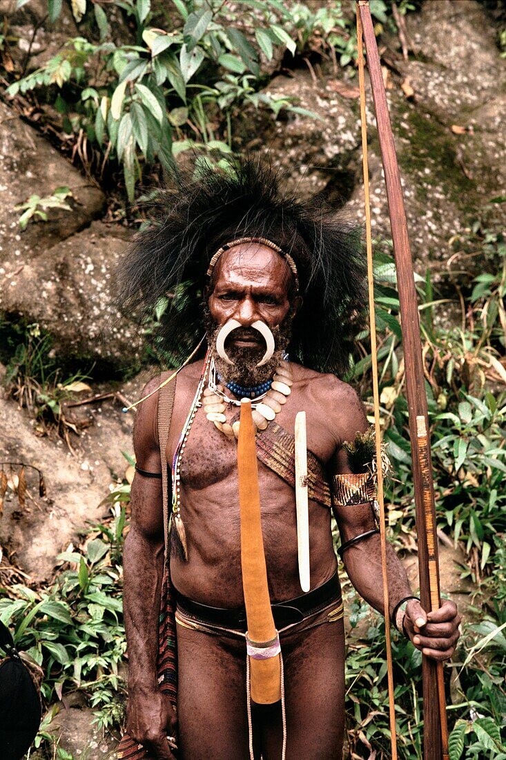 Porträt eines indigenen Mannes mit einem gebogenen Knochen in seinem Nasenpiercing und stehend mit Pfeil und Bogen, Irian Jaya, Neuguinea, Indonesien