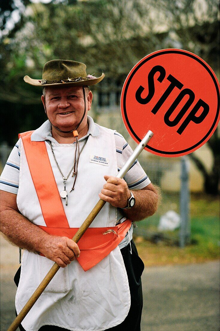 Rugged male crossing guard holding a stop sign, Australia
