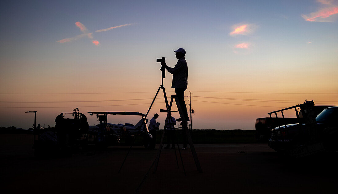Silhouette Fotograf auf einem Flugplatz während des Sonnenuntergangs
