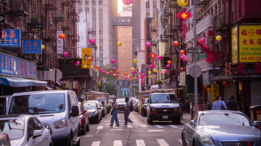 Zwei Menschen beim Überqueren der Straße in China Town, Manhattan, New York, bei Sonnenuntergang.