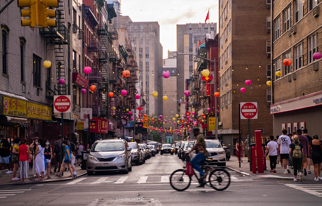 Ein Mann, der durch ein geschäftiges China Town in New York City radelt.