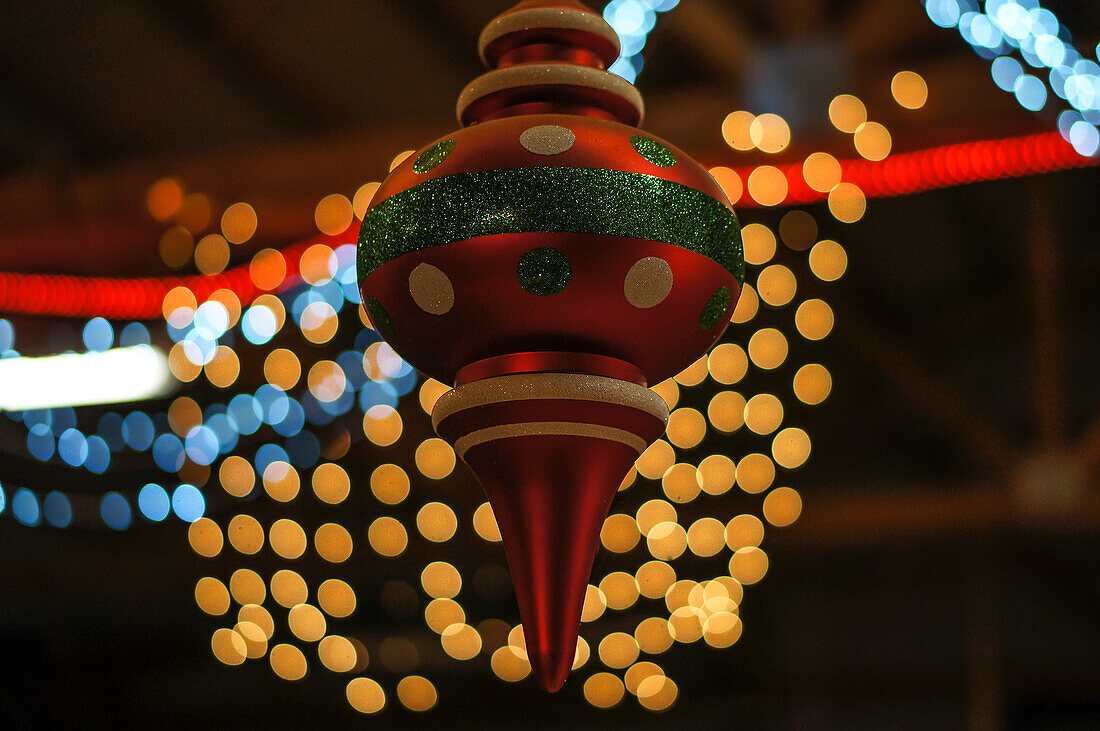 Lange rote Weihnachtsverzierung, umgeben von Bokeh-Lichtern.