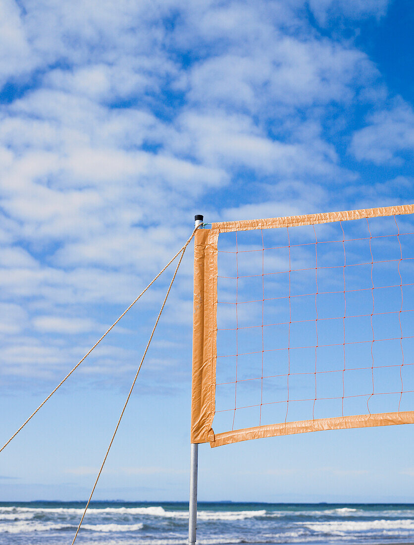 Beachvolleyballnetz eingerichtet und Wellen und blauer Himmel im Hintergrund