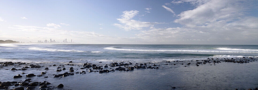 Panorama mit Blick über die Wellen und das Meer auf die Skyline von Surfers Paradise