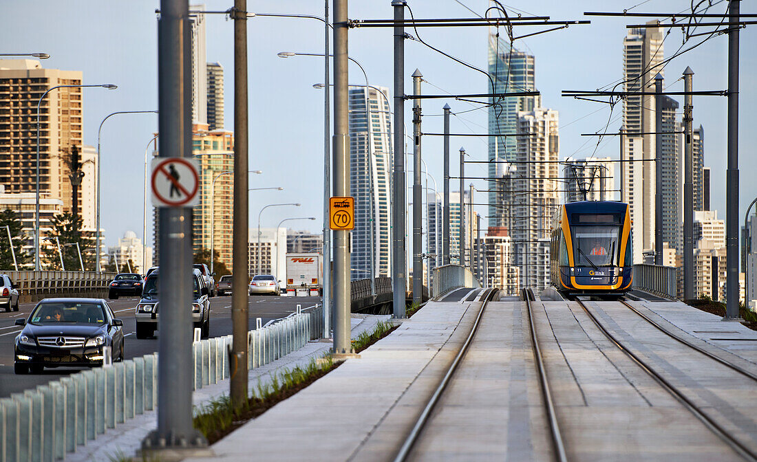 Tram travelling alongside road and Surfers Paradise city in the background