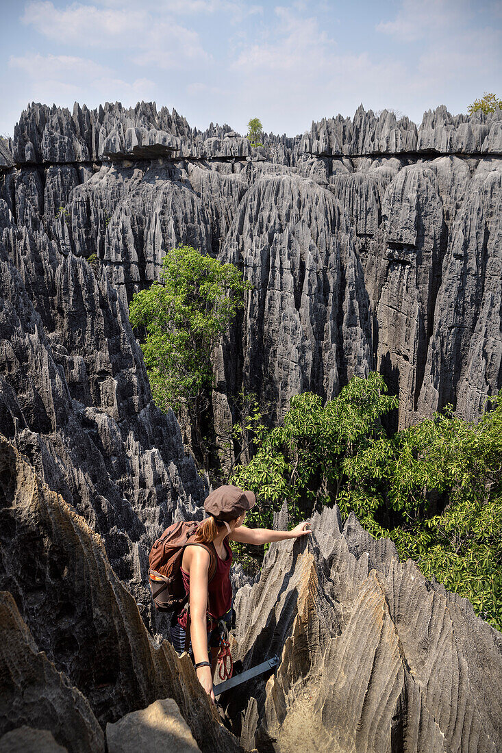 Frau steigt an Leiter im Nationalpark Tsingy de Bemaraha ab und blickt auf die Karstlandschaft, Madagaskar, Provinz Mahajanga, Afrika, UNESCO Weltnaturerbe