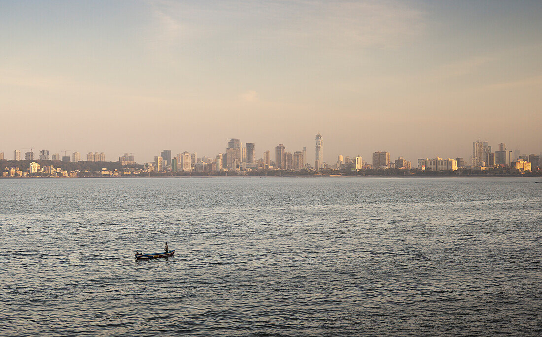 Blick über das Wasser mit einem einsamen Boot auf die Skyline von Mumbai City
