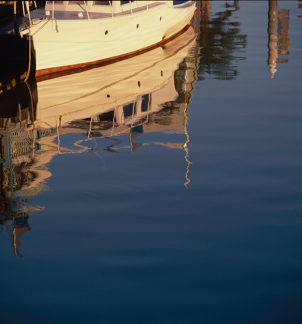 Small boat tied up to jetty and reflections in the calm water