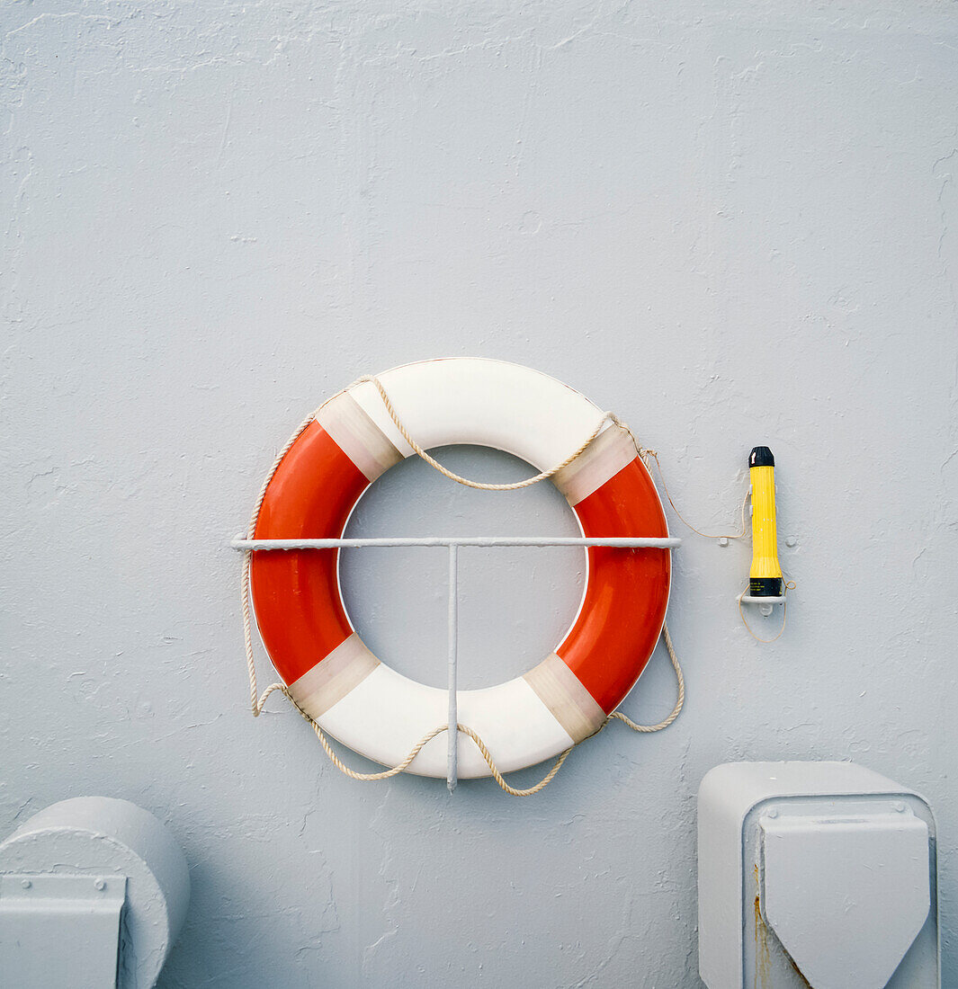 Close up of red and white life preserver ring hanging on side of ship