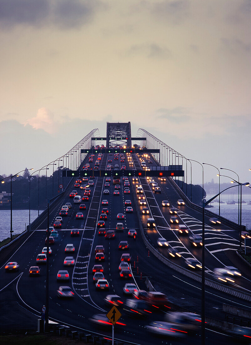 Der Verkehr fließt in der Abenddämmerung auf der Auckland Harbour Bridge in beide Richtungen