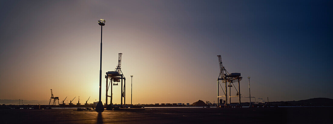 Panorama der Kräne bei Sonnenaufgang am großen Hafen