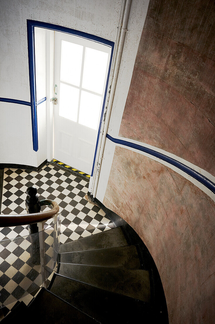 Blick die Treppe hinunter auf den schwarz-weißen Schachbrettfliesenboden im Eingang des Byron Bay Lighthouse