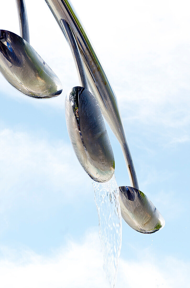 Looking up at water feature spilling water against blue sky