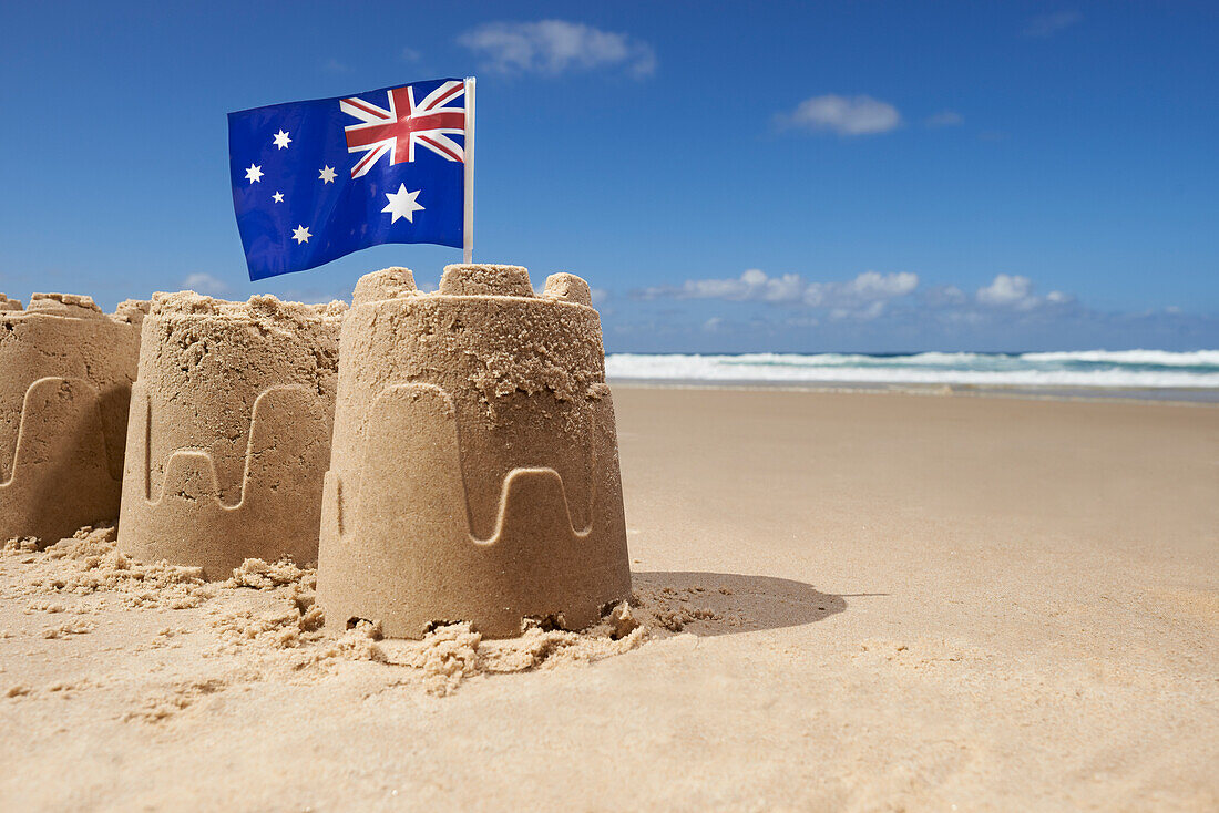 Australische Flagge auf einer Gruppe von drei Sandburgen am Strand