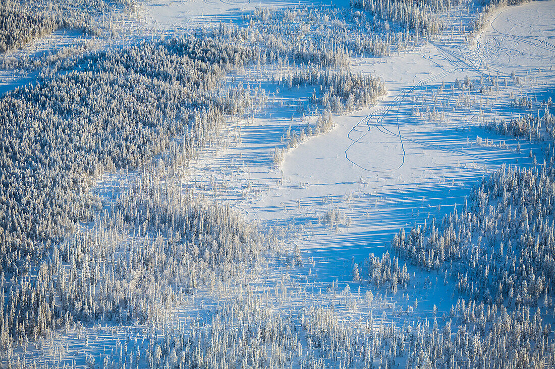 Aerial view of snow covered wilderness area with tracks in snow.