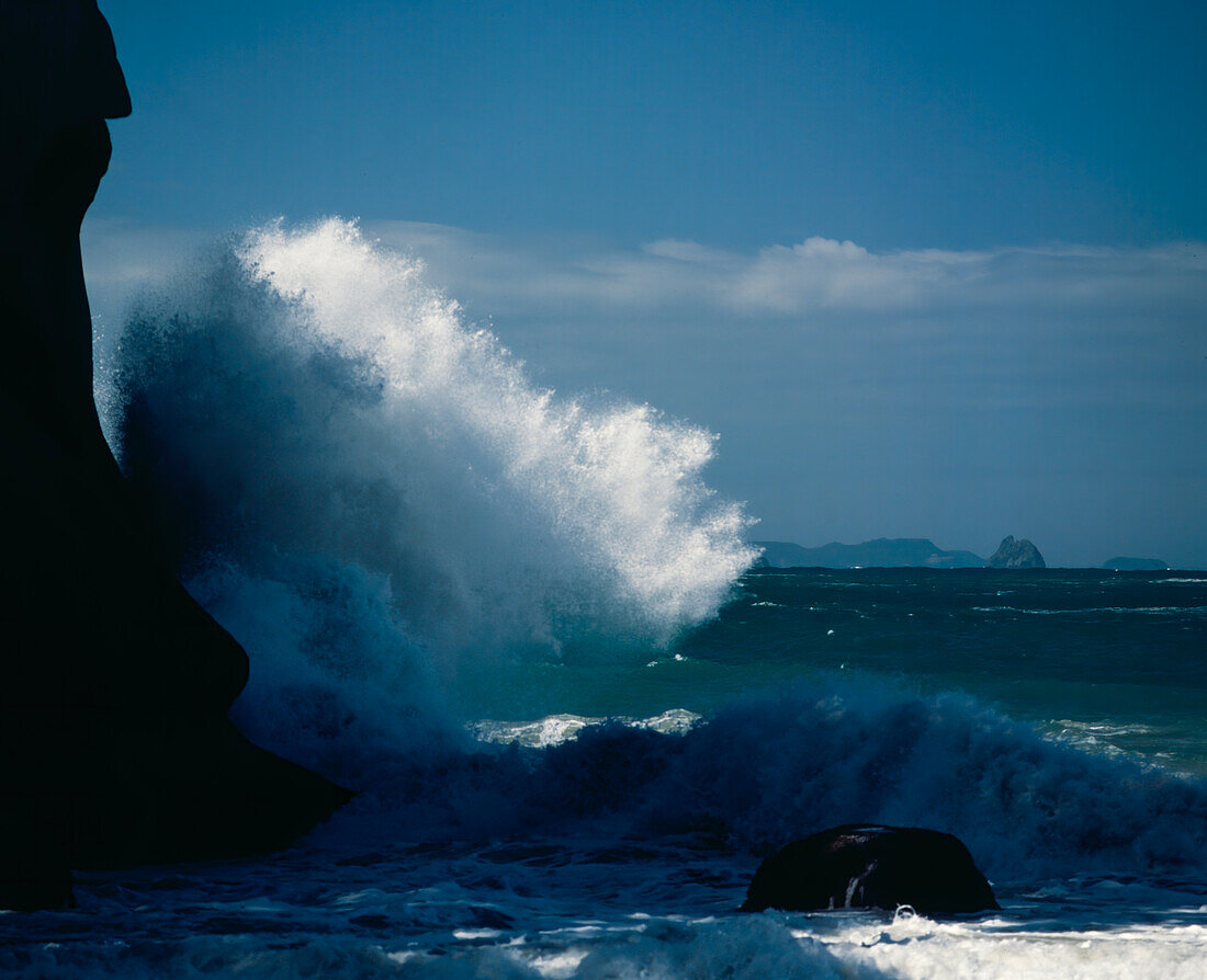 Wellen, die gegen felsige Klippen schlagen