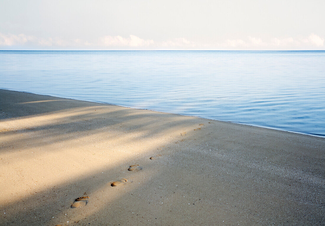 Footprints leading to calm tropical water