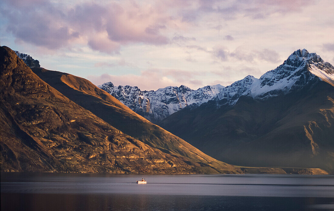 Steam boat on Lake Wakatipu and snow capped mountain range behind - New Zealand