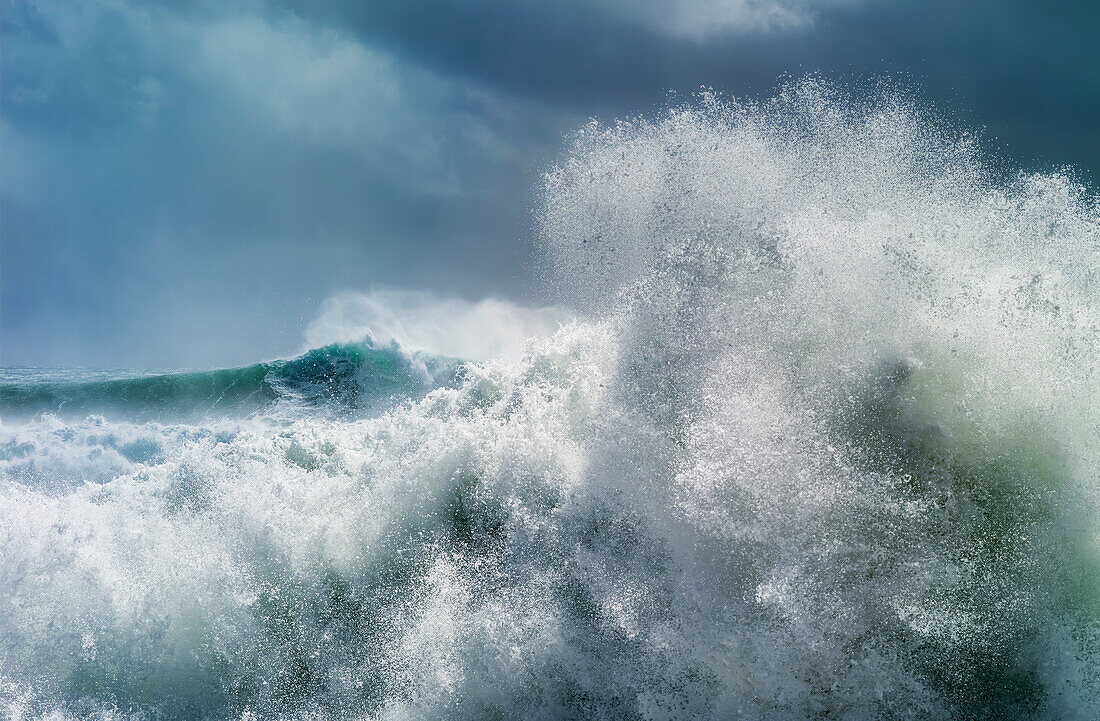 Huge wave curling over and breaking during cyclone Ola with stormy sky